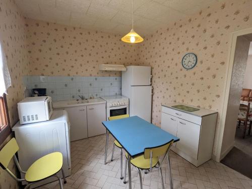 une cuisine avec une table bleue et des chaises jaunes dans l'établissement Maison spacieuse avec cour et cheminée au cœur du Parc Naturel de la Brenne - FR-1-591-229, à Mézières-en-Brenne