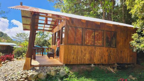 a small wooden house with a man standing on a deck at Hospedajes Richie Eco Camp in Providencia