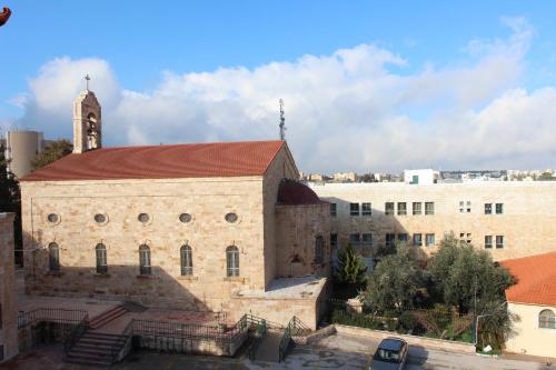 an old stone church with a clock tower in a city at Pilgrim's Guest House in Madaba
