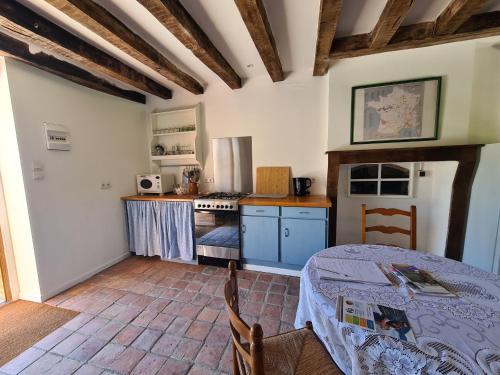 une cuisine avec une table et une cuisinière four supérieur dans l'établissement Gîte charmant en Berry avec terrasse, jardin, parking et chauffage inclus - FR-1-591-364, à Lignac