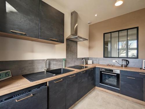 a kitchen with black cabinets and a sink at Charmant Gîte en Berry avec Étang, Terrasse et Spa à Proximité - FR-1-591-407 in Douadic