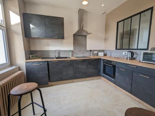 a kitchen with black cabinets and a stool in it at Charmant Gîte en Berry avec Étang, Terrasse et Spa à Proximité - FR-1-591-407 in Douadic