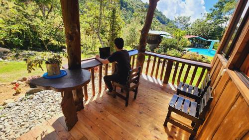 a man sitting on a porch using a laptop at Hospedajes Richie Eco Camp in Providencia