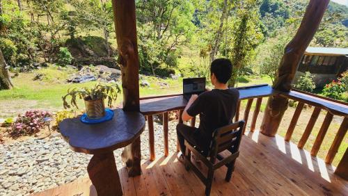 a person sitting in a chair on a porch looking out the window at Hospedajes Richie Eco Camp in Providencia
