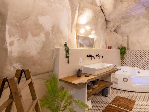 a bathroom in a cave with a sink and a tub at Gîte troglodyte unique avec jacuzzi, billard et jardin, près de Doué La Fontaine et Saumur - FR-1-622-69 in Les Ulmes