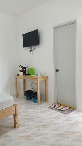 a room with a table and a television and a table with shoes at RMB GUEST HOUSE in Siquijor