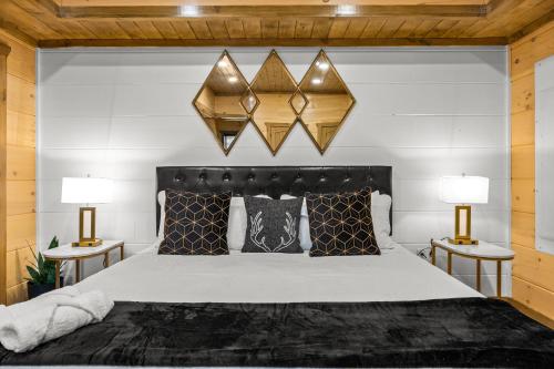 a bedroom with a large bed with two lamps at SmokiesBoutiqueCabins would love to host you at our NEW cabin! 3 King Suites, Indoor Pool, Game Room, Lounge with 75" TV! Close to Dollywood and the Parkway! in Pigeon Forge