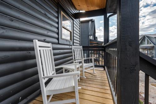 two white chairs sitting on a porch of a house at SmokiesBoutiqueCabins would love to host you at our NEW cabin! 3 King Suites, Indoor Pool, Game Room, Lounge with 75" TV! Close to Dollywood and the Parkway! in Pigeon Forge