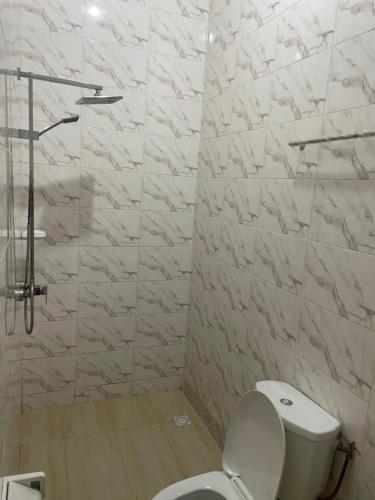 La salle de bains blanche est pourvue d'une douche et de toilettes. dans l'établissement Timba chic-villa, à Abomey-Calavi