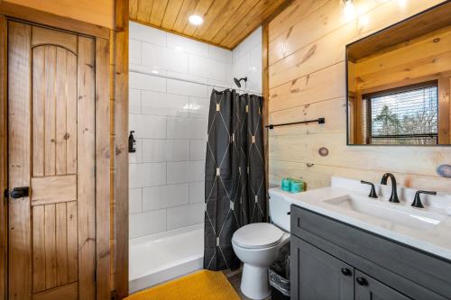 a bathroom with a toilet and a sink and a shower at SmokiesBoutiqueCabins would love to host you at our NEW cabin! 3 King Suites, Indoor Pool, Game Room, Lounge with 75" TV! Close to Dollywood and the Parkway! in Pigeon Forge
