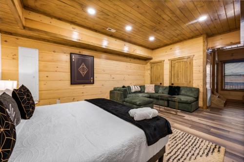 a bedroom with a bed and a couch in a room at SmokiesBoutiqueCabins would love to host you at our NEW cabin! 3 King Suites, Indoor Pool, Game Room, Lounge with 75" TV! Close to Dollywood and the Parkway! in Pigeon Forge
