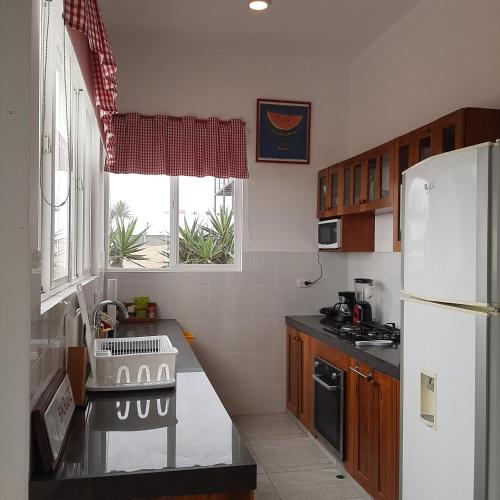 a kitchen with a sink and a white refrigerator at CASA DE PLAYA Durante todo el año in Punta Negra