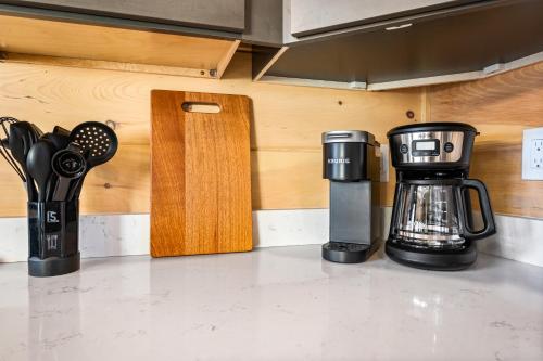 a coffeemaker and a coffee maker on a kitchen counter at SmokiesBoutiqueCabins would love to host you at our NEW cabin! 3 King Suites, Indoor Pool, Game Room, Lounge with 75" TV! Close to Dollywood and the Parkway! in Pigeon Forge