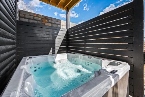 a hot tub in the backyard of a house at SmokiesBoutiqueCabins would love to host you at our NEW cabin! 3 King Suites, Indoor Pool, Game Room, Lounge with 75" TV! Close to Dollywood and the Parkway! in Pigeon Forge