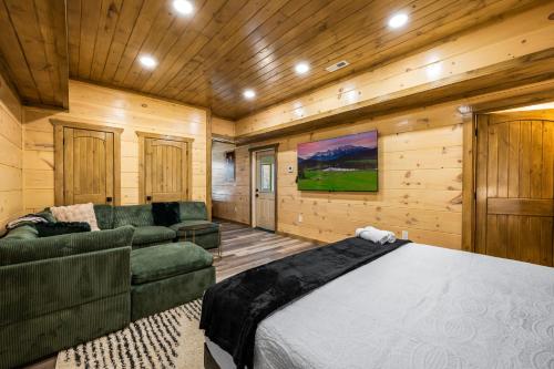 a bedroom with a bed and a couch at SmokiesBoutiqueCabins would love to host you at our NEW cabin! 3 King Suites, Indoor Pool, Game Room, Lounge with 75" TV! Close to Dollywood and the Parkway! in Pigeon Forge