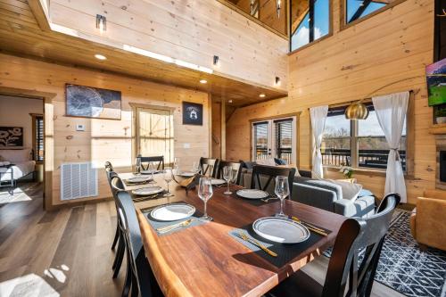 a dining room with a wooden table and chairs at SmokiesBoutiqueCabins would love to host you at our NEW cabin! 3 King Suites, Indoor Pool, Game Room, Lounge with 75" TV! Close to Dollywood and the Parkway! in Pigeon Forge