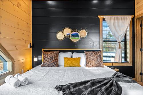 a bedroom with a bed with a black wall at SmokiesBoutiqueCabins would love to host you at our NEW cabin! 3 King Suites, Indoor Pool, Game Room, Lounge with 75" TV! Close to Dollywood and the Parkway! in Pigeon Forge