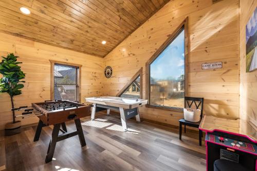a room with a ping pong table in a log cabin at SmokiesBoutiqueCabins would love to host you at our NEW cabin! 3 King Suites, Indoor Pool, Game Room, Lounge with 75" TV! Close to Dollywood and the Parkway! in Pigeon Forge