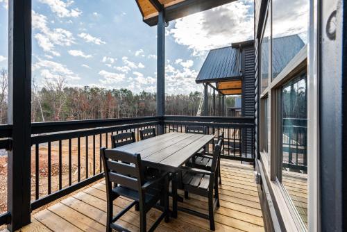 a wooden deck with a wooden table and chairs on it at SmokiesBoutiqueCabins would love to host you at our NEW cabin! 3 King Suites, Indoor Pool, Game Room, Lounge with 75" TV! Close to Dollywood and the Parkway! in Pigeon Forge