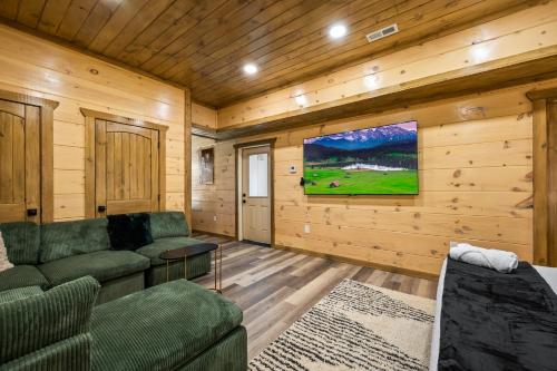 a living room with a couch and a flat screen tv at SmokiesBoutiqueCabins would love to host you at our NEW cabin! 3 King Suites, Indoor Pool, Game Room, Lounge with 75" TV! Close to Dollywood and the Parkway! in Pigeon Forge