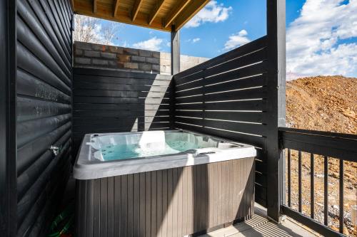 a hot tub on a deck with a black fence at SmokiesBoutiqueCabins would love to host you at our NEW cabin! 3 King Suites, Indoor Pool, Game Room, Lounge with 75" TV! Close to Dollywood and the Parkway! in Pigeon Forge