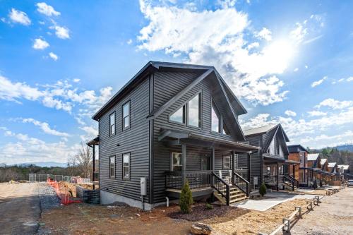 a black house with a gambrel roof at SmokiesBoutiqueCabins would love to host you at our NEW cabin! 3 King Suites, Indoor Pool, Game Room, Lounge with 75" TV! Close to Dollywood and the Parkway! in Pigeon Forge
