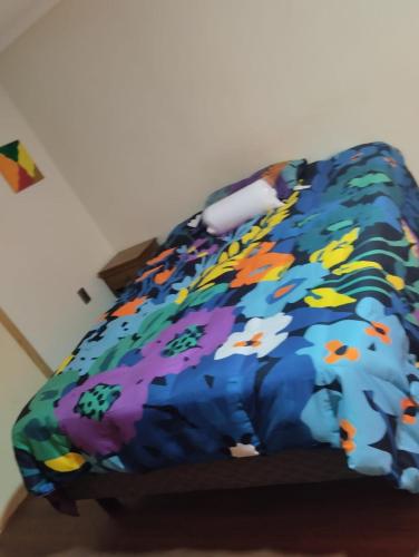 a bed with a colorful comforter and a kite at Amatista house in Copiapó