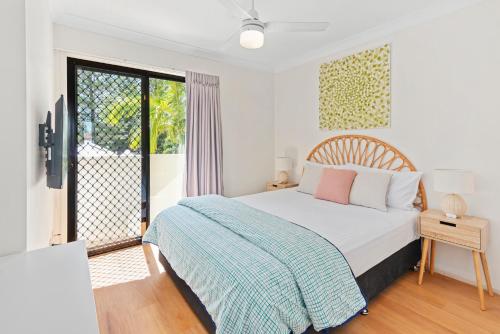 a white bedroom with a bed and a balcony at Island Beach Resort in Gold Coast