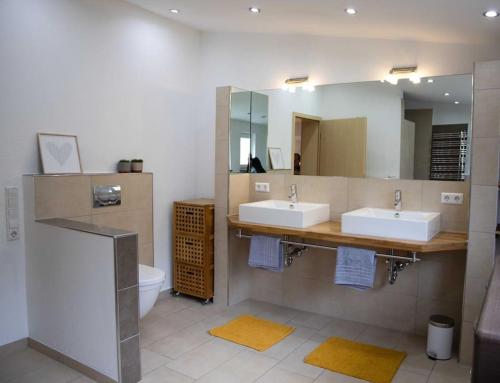 een badkamer met 2 wastafels, een spiegel en een toilet bij Schönes und gemütliches Haus in mitten der Natur 