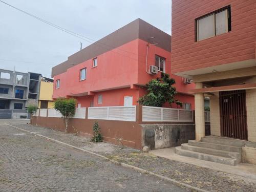 a red building with stairs next to a street at Apartment in Achada São Filipe in Praia