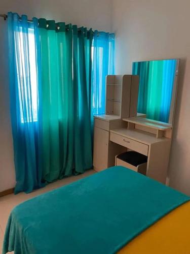 Schlafzimmer mit blauen Vorhängen, einem Schreibtisch und einem Spiegel in der Unterkunft Jbct & SOLANGE APART in Praia