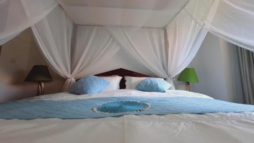a large bed with white curtains and blue pillows at Villia magnolia sanur bali 巴厘島玉蘭別墅 in Denpasar