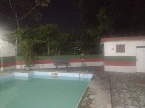 a swimming pool at night with a table and a bench at Bitencourt in Rio de Janeiro
