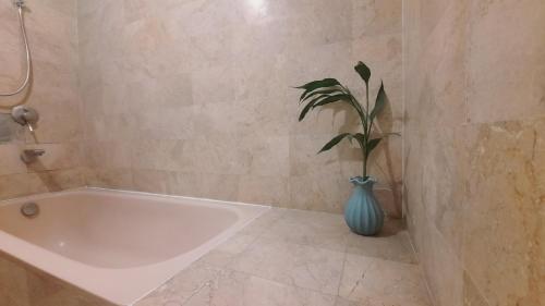 a bathroom with a white tub and a plant in a vase at Villia magnolia sanur bali 巴厘島玉蘭別墅 in Denpasar