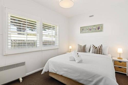 a white bedroom with a bed and a window at Sorrento Beach Cottages No.1 - in the heart of Sorrento in Sorrento