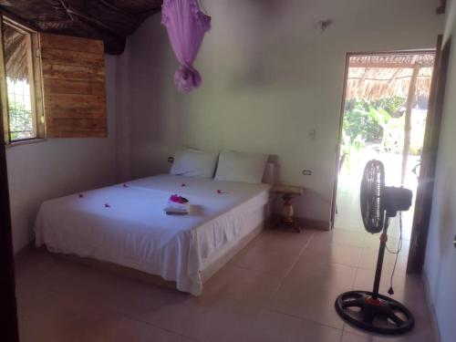 - une chambre avec un lit blanc et un parapluie violet dans l'établissement ECOHOTEL LAS FLORES Econativo, à Isla Grande