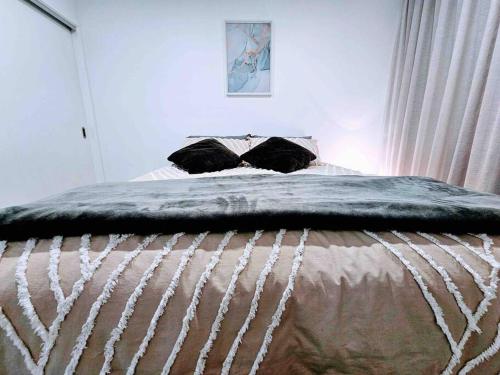 a bed with a blanket on it in a bedroom at Short Drive to Queenstown CBD - Cosy Guesthouse with Private Entrance and King Bed in Frankton