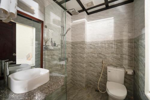 y baño con aseo, lavabo y ducha. en RAON Hoian Beach en Hoi An