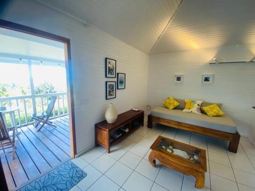 Cette chambre comprend un lit, une table et un balcon. dans l'établissement Bungalow Tiare, à Uturoa