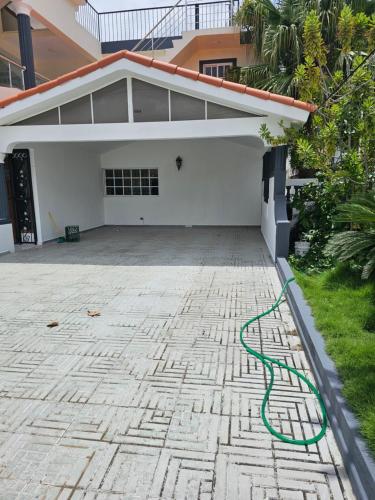 a green hose laying on the ground in front of a house at Jlp in San Francisco de Macorís
