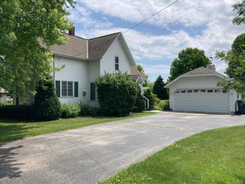 a white house with a garage at Cozy Algoma Retreat! Minutes to Beach and Downtown! in Algoma