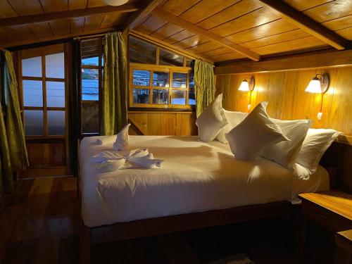 una camera da letto con letto, lenzuola e cuscini bianchi di Guayabo Hostal Spa a Mindo