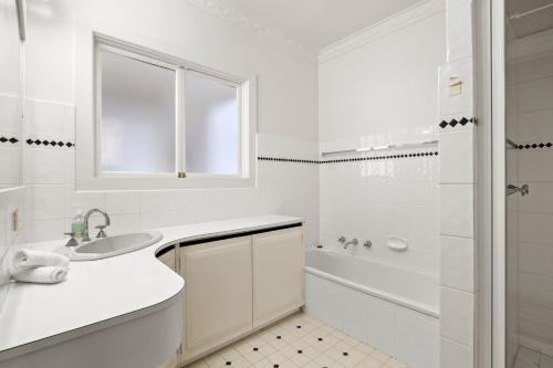 een witte badkamer met een wastafel en een douche bij Price Central Torquay 32 in Torquay