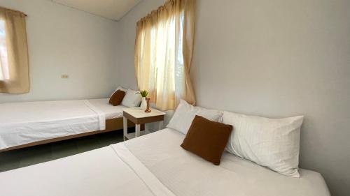 ein kleines Schlafzimmer mit 2 Betten und einem Fenster in der Unterkunft Manalo's Lodge and Restaurant in Puerto Galera