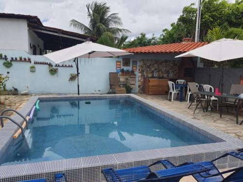 a swimming pool with chairs and an umbrella next to a house at Casa em Ponto de Lucena in Lucena