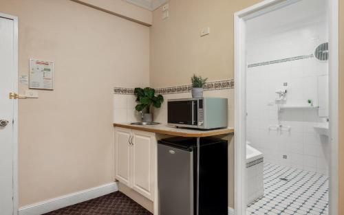 a bathroom with a microwave on a counter with a tub at Katoomba Town Centre Motel in Katoomba