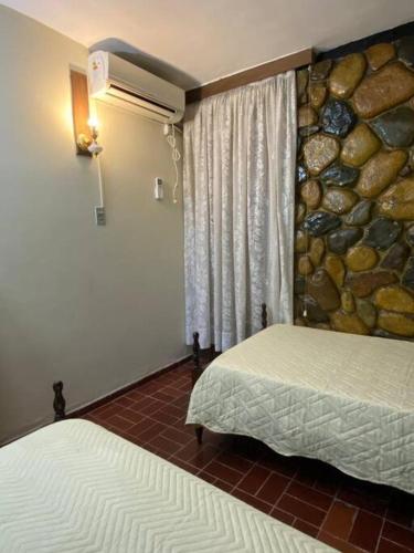 a bedroom with two beds and a stone wall at Casa Tupungato con Churrasquera in Tupungato