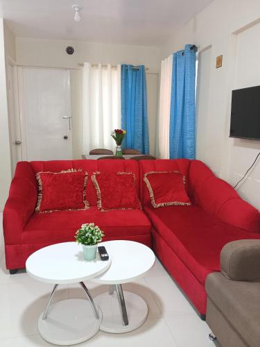 a red couch in a living room with a table at Pagadian Staycation in Camella 1 in Pagadian