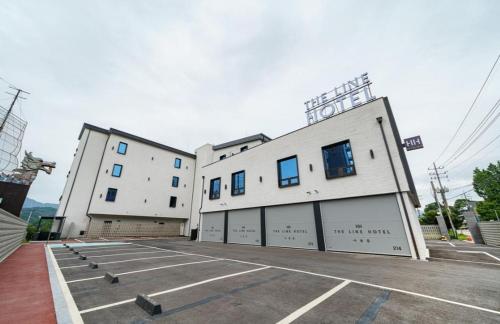 a large white building with two garage doors in a parking lot at The Line Hotel in Yangpyeong