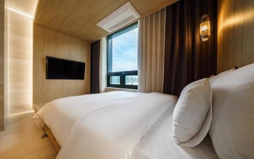 a bedroom with a large white bed and a window at The Line Hotel in Yangpyeong